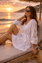 white knee length belted beach dress with gold embroidery for cooler evenings by lindsey brown